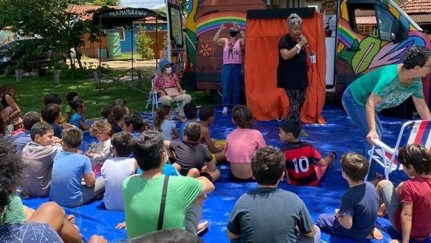 Público acompanha uma apresentação ao lado do motorhome colorido do Esperança Sobre Rodas